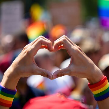 Hands Making Heart Shape in Colorful Pride Celebration Outdoors