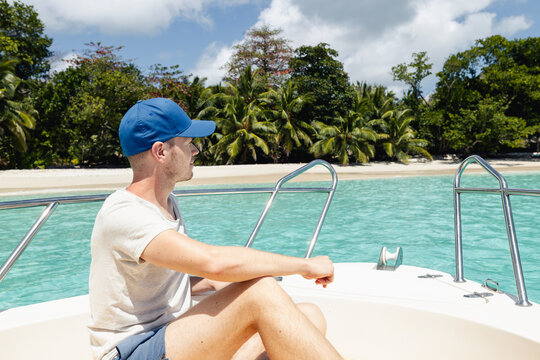 Tourist sitting on bow of speedboat approaching idyllic Anse Lazio beach in Seychelles. Tropical island vacation, luxury travel destination, ocean cruise and summer paradise concept.