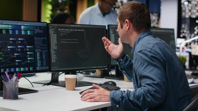 System administrator in workplace doing AI tech quality assurance. Man in office typing on keyboard, writing AI script with programming languages.