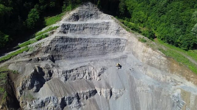 Excavator operating in a quarry aerial view. Drone view of excavator in stone quarry.