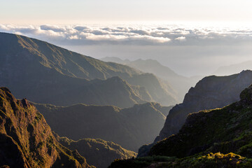 Fototapeta premium Pico do Arieiro sunrise over Madeira's rugged peaks. Dramatic mountain ridges, clouds drifting through valleys. Hiking trails wind through volcanic terrain. Portugal's island landscape at dawn.