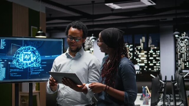 Tech agency staff members using tablet, brainstorming how to optimize AI performance in office. technicians use machine learning on device for debugging, analyzing code for coding workflows.