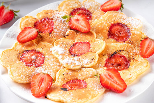 Viral summer breakfast Strawberry Flower Pancakes, sweet tasty fluffy pancakes with slice of fresh raw strawberry in the middle, kids morning and lunch food idea