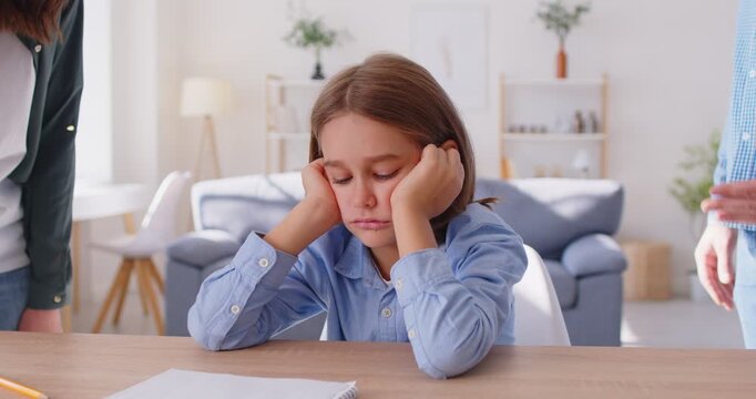 Angry parents scolding child for bad school results sitting at desk at home. Man and woman quarrelling and arguing with tired upset boy during homework. Family and children conflicts. 4k video.
