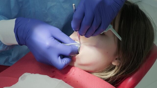 Dentist adjusting mouth retractor for child patient