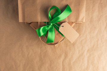 Fototapeta premium Craft gift box with green ribbon and blank tag in a bag