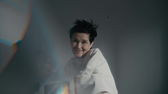 Medium portrait of middle aged Caucasian woman in straitjacket laughing hysterically then looking sad. Clip is suitable for mental health awareness campaigns or psychiatric hospital documentaries