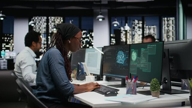Panicked female engineer in office requests help from colleagues to block hacker intrusion with teamwork context.