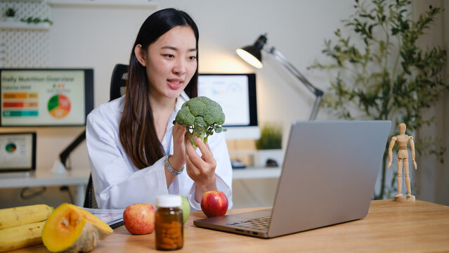 Nutritionist holding fresh broccoli while giving online health advice, representing diet planning and wellness advice.