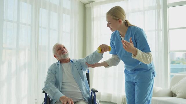 Support rehabilitation healthcare. Nurse helps old man patient in wheelchair picking up dumbbells. Paralyzed man in chair for people with disability doing sports exercise with nurse. Medical caregiver