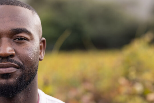 African man smiling softly while standing in meadow with light-colored shirt, copy space