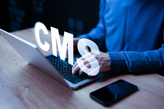 Working on a content management system with a laptop and smartphone in a dark room