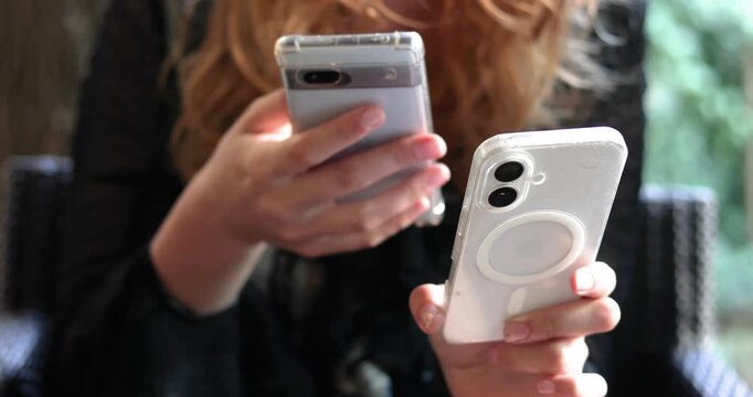 Holding two smartphones in one hand and transferring information from one to the other.