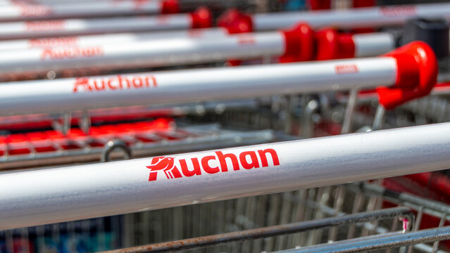 Barberey-Saint-Sulpice, France - 7 juin 2026: Logos Auchan sur des charriots de courses &agrave; l'ext&eacute;rieur d'un hypermarch&eacute; Auchan. Auchan est un groupe fran&ccedil;ais multinational de grande distribution