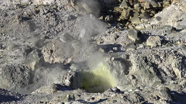 Geothermal vent with volcanic sulfur deposits and steam rising from the rocky ground in a volcanic landscape