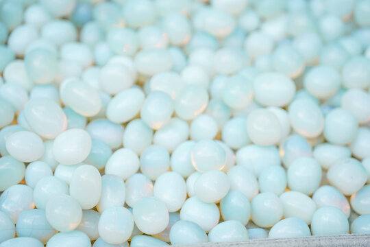 Abundant Pile Of Smooth Pale Blue Polished moonstone Displayed Under Bright Soft Indoor Lighting texture