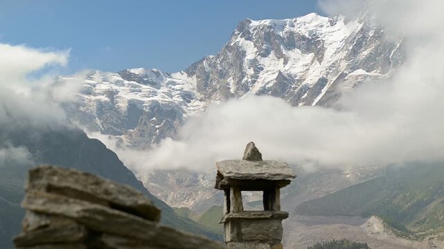 Monte Rosa east face with glacier and clouds above alpine stone hut chimney, majestic mountain landscape in the Italian Alps, Italy, summer sunny day