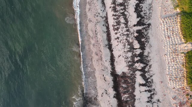 Vertical drone flight along Nordstrand with algae patterns water and dune landscape.