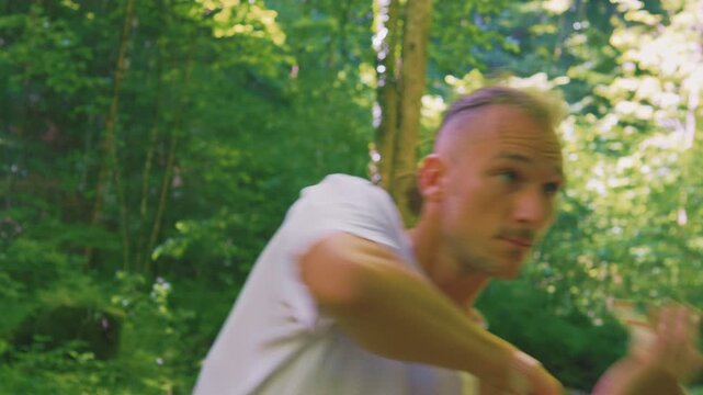 In the serene forest, a man practices balance and relaxation with his arms outstretched, embodying a healthy lifestyle and zen-like focus.