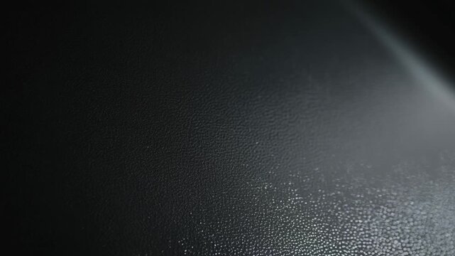 Slow pan close up of textured leather surface with scattered water droplets and subtle light reflections inside vehicle interior dashboard