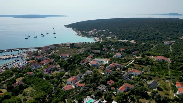 Stunning aerial view of Sotorisce Bay on the eastern shore of Silba Island, Croatia, featuring crystal clear turquoise water, a sandy seabed, and a protected harbor filled with white sailboat