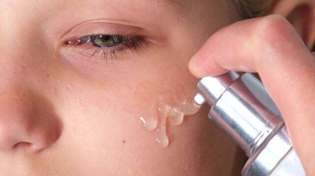 Close-up of a woman applying facial serum with a cosmetic dispenser, highlighting skincare, hydration, beauty treatment and daily self-care routine.