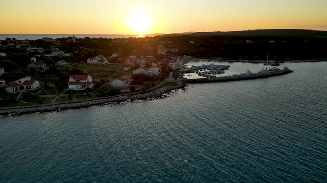 A stunning aerial drone shot capturing the warm golden sunset over the Sotorisce bay and Mulj harbor area on Silba Island, Croatia. The perspective showcases the sheltered marina filled with boats