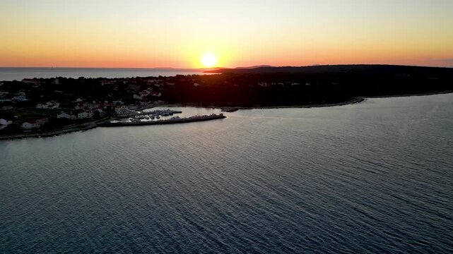 A stunning aerial drone shot capturing the warm golden sunset over the Sotorisce bay and Mulj harbor area on Silba Island, Croatia. The perspective showcases the sheltered marina filled with boats