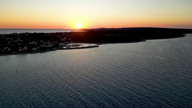 A stunning aerial drone shot capturing the warm golden sunset over the Sotorisce bay and Mulj harbor area on Silba Island, Croatia. The perspective showcases the sheltered marina filled with boats