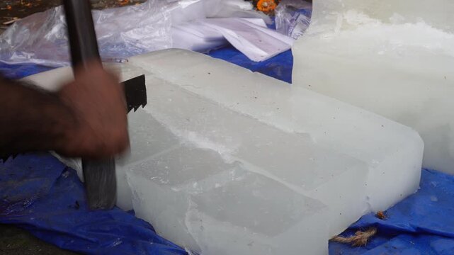 Worker cutting ice block with hand saw in action