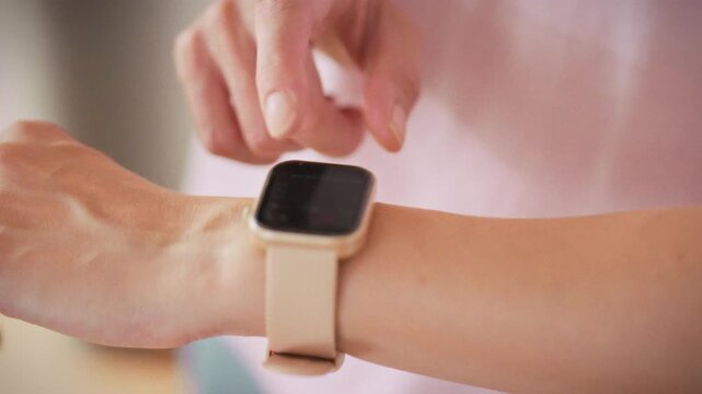 In a bright gym studio, a teenage girl checks her watch displaying workout stats, heart-rate and calorie burn, highlighting how wearable technology guides her training and performance goals