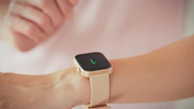 In close-up, focused girl watches her smartwatch's bright screen as digital countdown ticks down, marking moment her workout is about to start, highlighting the anticipation of her fitness routine