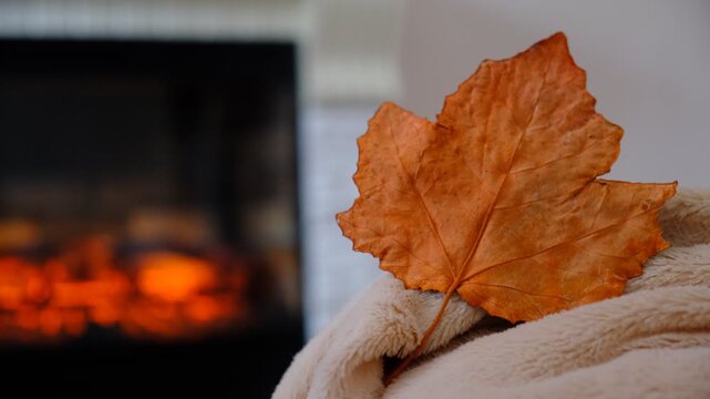 Fireplace and fluffy warm beige blanket. Autumn whispers through the window, while inside, warmth and comfort reign supreme. Snuggled under a soft, warm blanket by the crackling fireplace