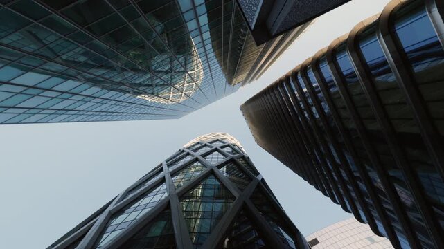 Dramatic low angle view of modern office towers forming geometric patterns in a financial district. Corporate architecture, business growth, investment and urban innovation.
