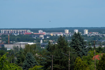 Wiosenna panorama Ostrowca Świętokrzyskiego w Polsce, prezentująca połączenie elementów miejskich i naturalnych. W tle dominują średniowysokie budynki mieszkalne, przeplatane drzewami i zielenią.  © Grzegorz