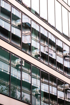 Across a diagonal view, urban architecture frames a building facade with glass windows, balconies and reflection, turning repeated pattern into exterior rhythm