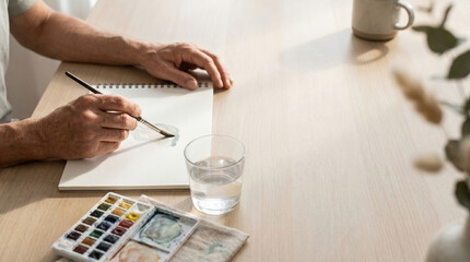 Fototapeta premium Hands Painting Watercolor Artwork on Wooden Desk in Home Studio