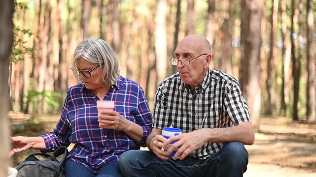 Senior couple using reusable collapsible cup during forest hiking video Full HD stop