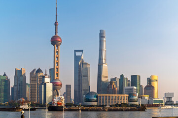 Fototapeta premium Sun rise of Shanghai city modern skyscraper cityscape in blue sky autumn season behind pollution haze, view from the bund in Shanghai, China.