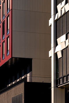 Dark building corner with red windows and sharp shadow defines an urban architecture facade, where wall surfaces create graphic contrast