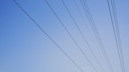 Fototapeta premium Parallel high voltage power lines against clear blue sky background