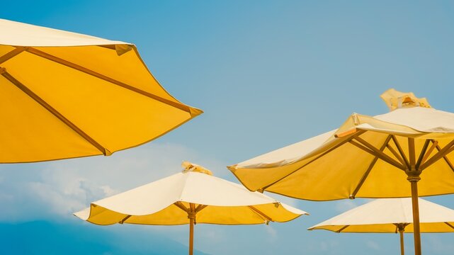 Yellow patio umbrellas against a soft, bright blue sky.
