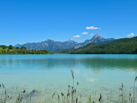 germany, sunlit weissensee beach panorama with crystal waters forested mountains and endless summer enjoyment