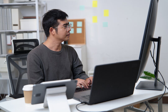 Focused Programmer Working on Code at a Desk Setup in a Professional Environment