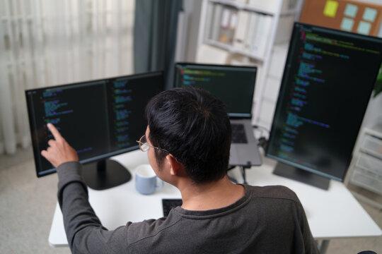 Focused Developer Working on Multiple Monitors with Code to Enhance Productivity