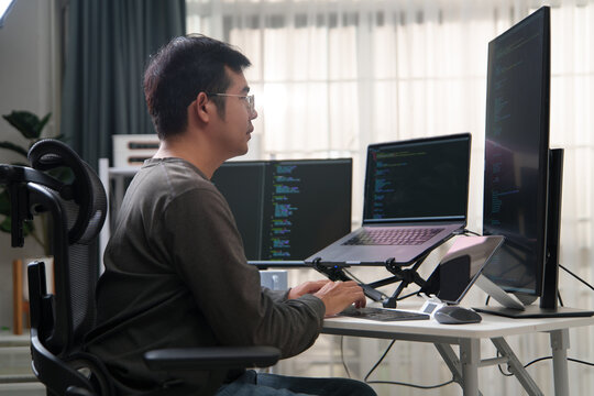 Focused Developer Engaged in Programming Tasks with Multiple Screens Displaying Code