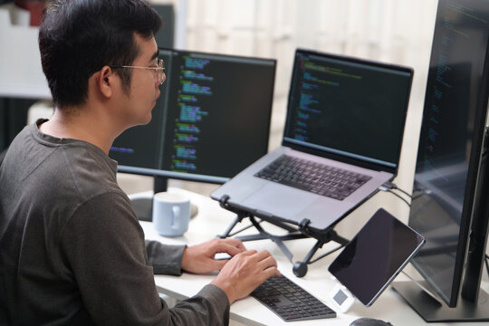 Focused Programmer Working on Multiple Screens with Code in an Office Setting