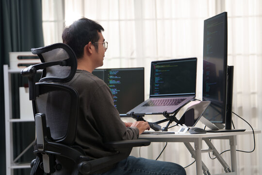 Focused Developer Working on Multiple Monitors at a Workspace with Advanced Technology
