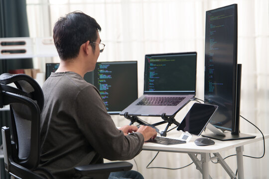 Focused Programmer Working with Multiple Monitors in an Office Environment for Coding Tasks