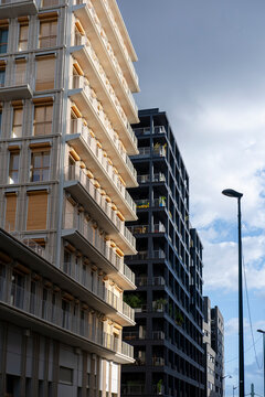 Paris apartment buildings stand along a narrow street, where residential balconies, facade shadows, windows and urban architecture draw vertical depth